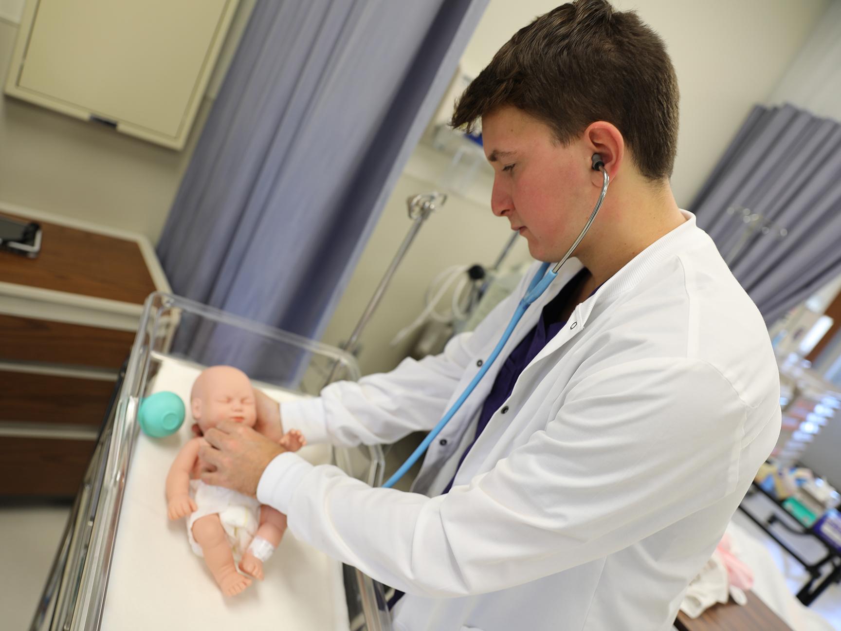 A student utilizing a SIM baby in the nursing lab